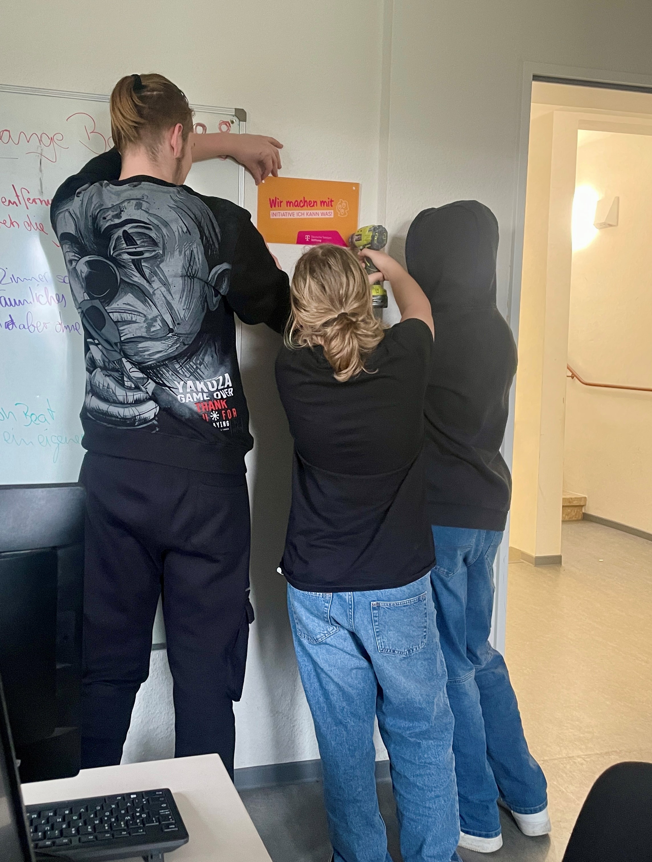 Die Jugendlichen im OJH hängen das Projektschild der Deutsche Telekom Stiftung im Medienraum auf.